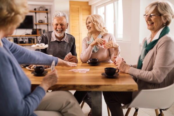 Group of happy mature people laughing while enjoying in card game at the table.
