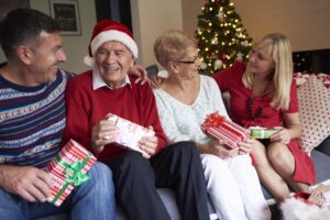 Adult children visiting ageing parents at Christmas, sitting together and exchanging gifts
