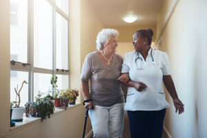 Nurse walking with elderly woman in aged care home