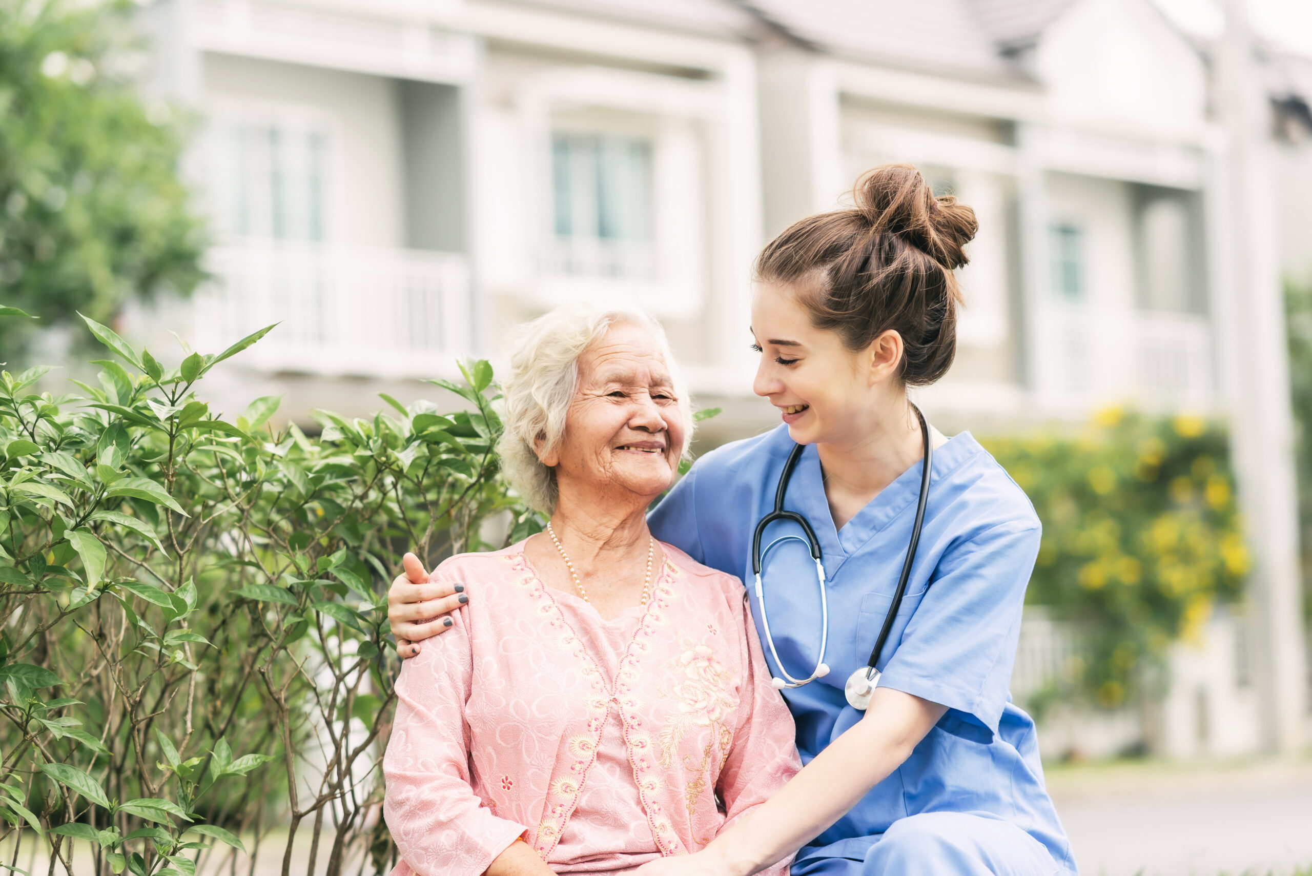 Happy nurse caregiver laughing with Asian elderly woman outdoor