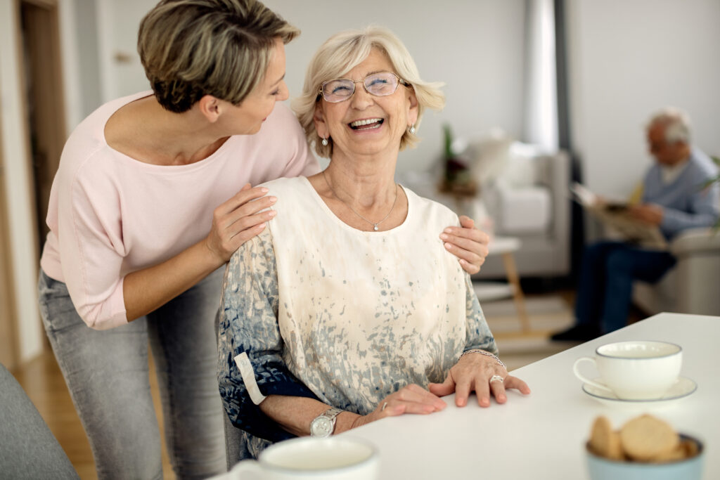 Carer standing behind an older woman at home, planning residential respite care for the holidays