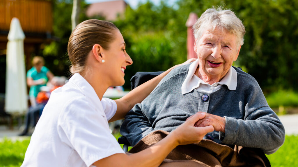 Carer with elderly woman in wheelchair on social outing