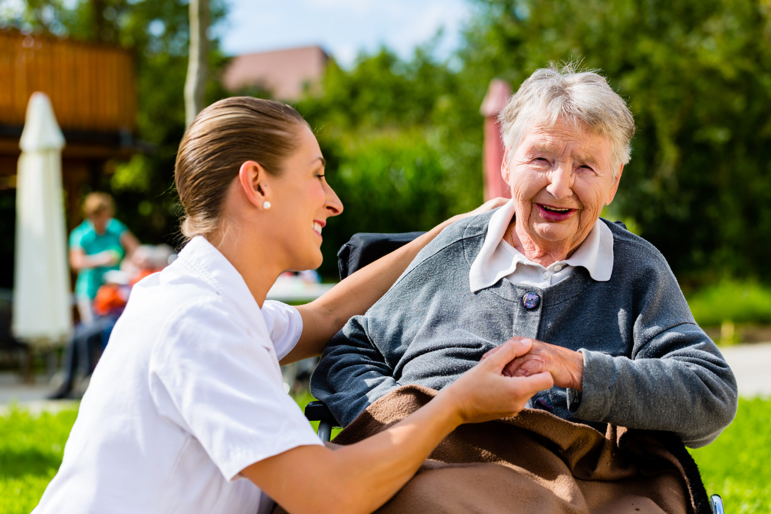 Carer with elderly woman in wheelchair on social outing