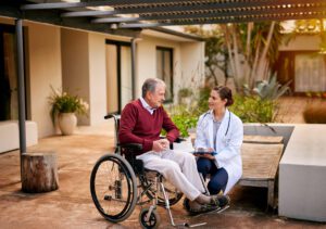 Older man in wheelchair with doctor at residential aged care home