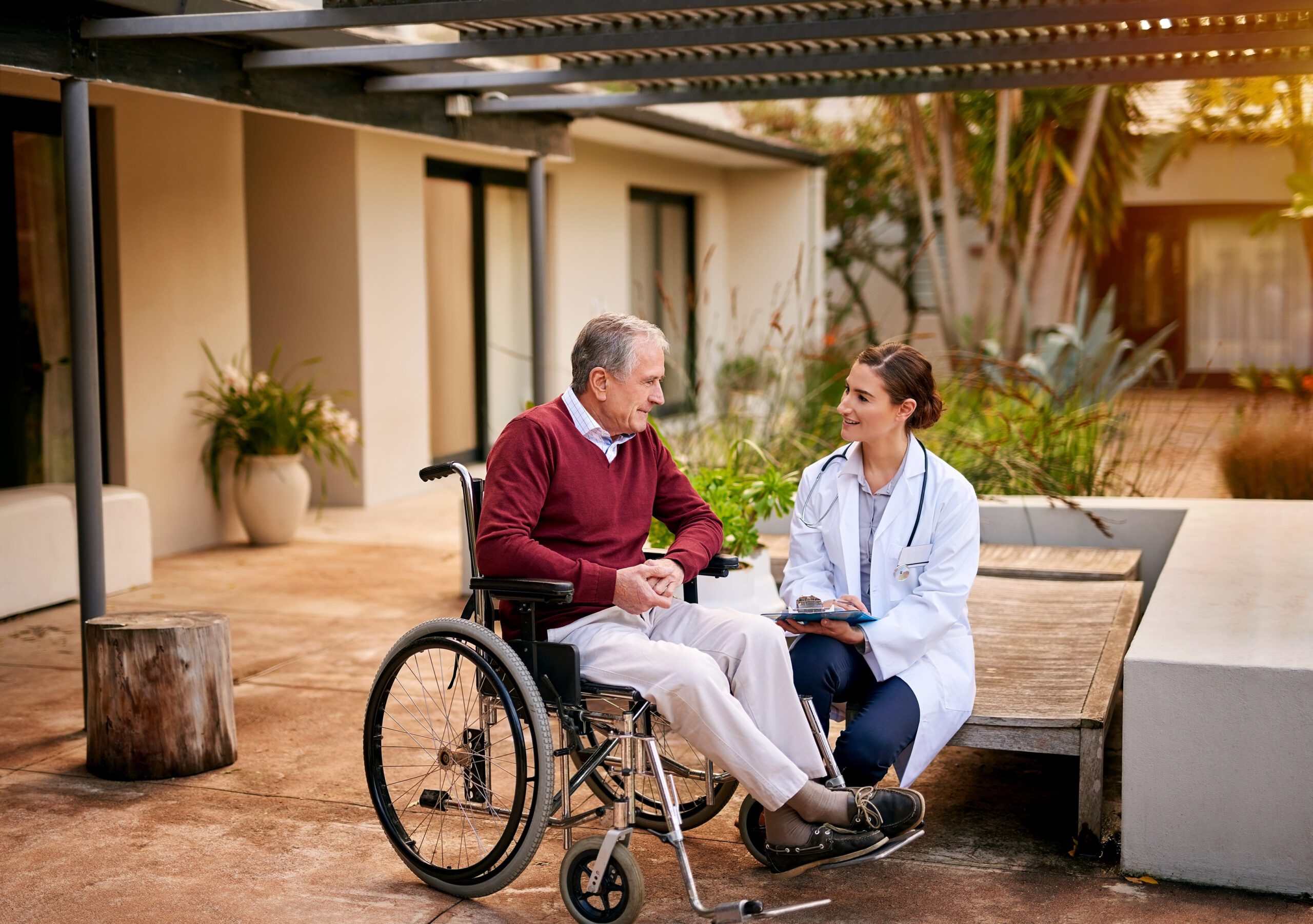 Older man in wheelchair with doctor at residential aged care home
