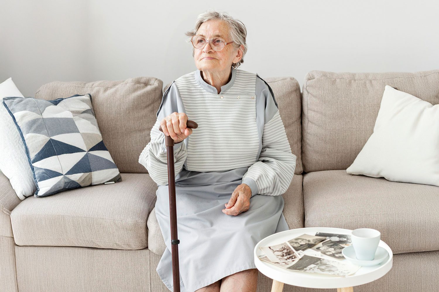 portrait-elderly-grandmother-sitting-sofa Elderly woman with walking stick sitting on sofa