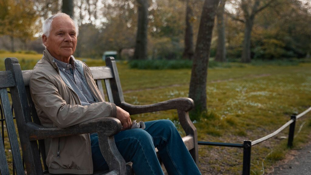 Senior man on park bench waiting for home care funding