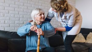 Elderly woman with walkingstick and in-home carer