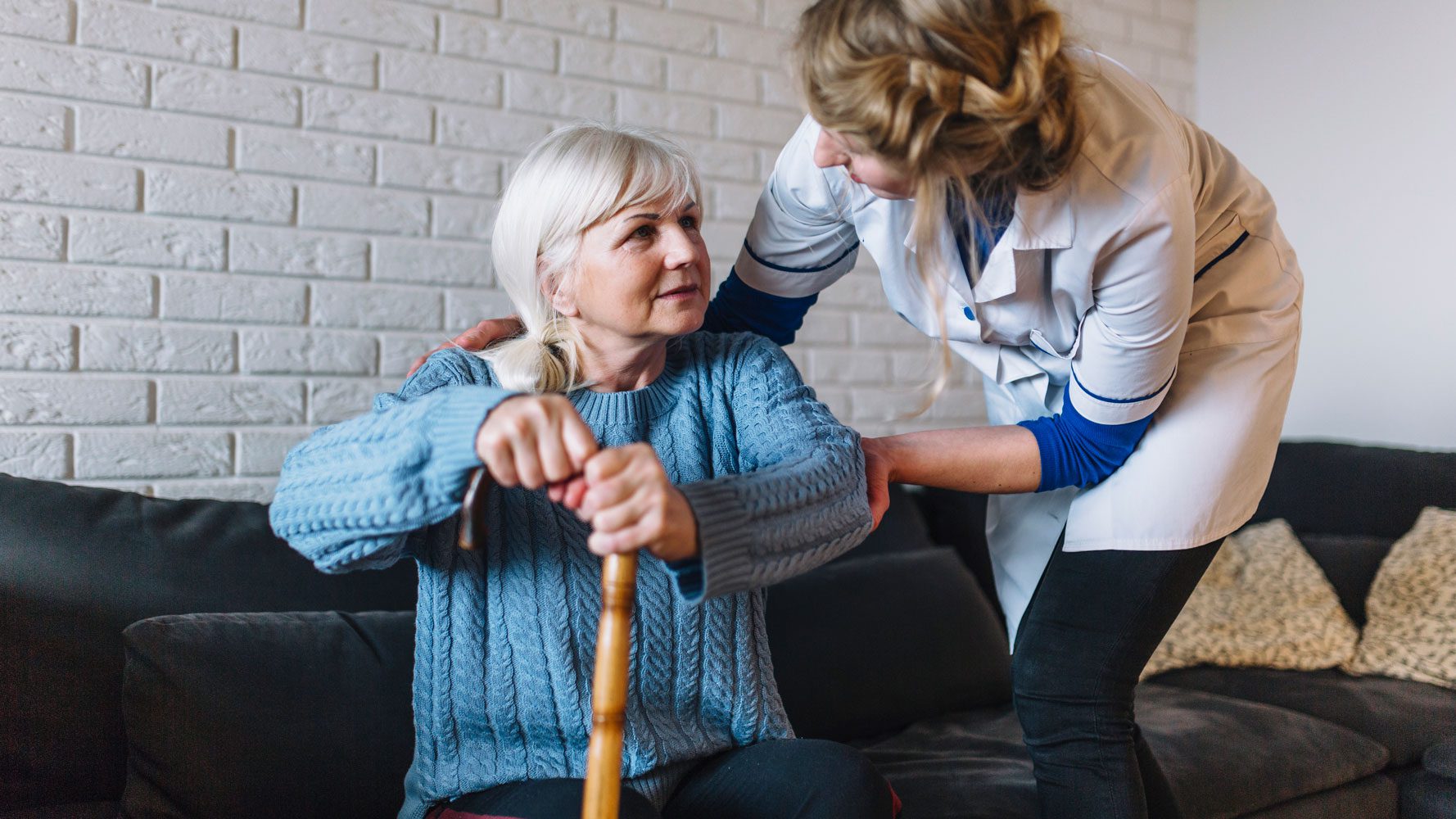 Elderly woman with walkingstick and in-home carer