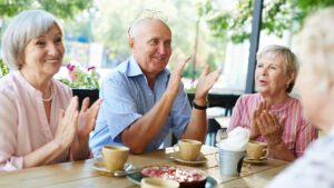 retirees around a table with coffee and cake in community coffee shop