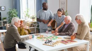 Seniors with care staff around a table playing board games