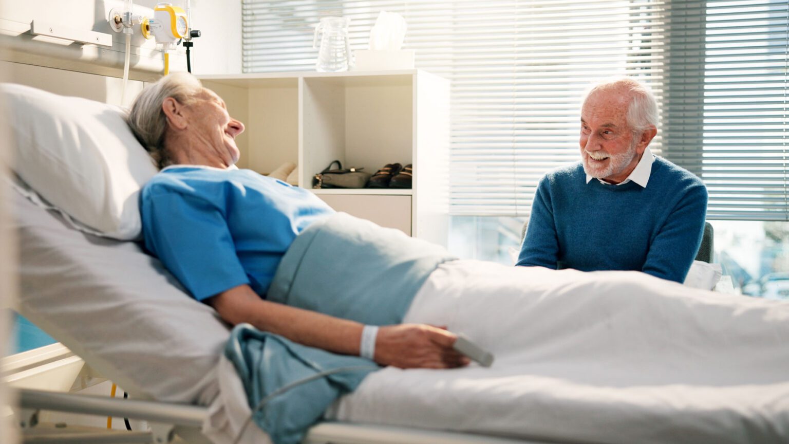 Elderly man visiting his wife in hospital bed