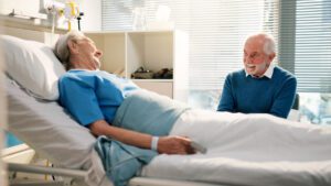 Elderly man visiting his wife in hospital bed