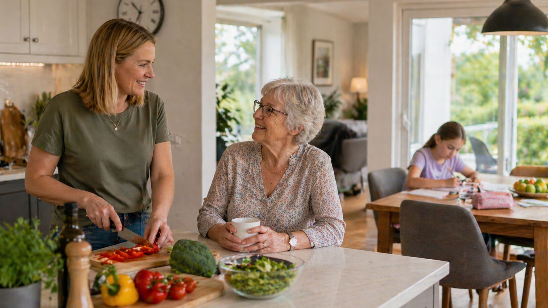 woman preparing dinner in kitchen with older mother and young daughter doing homework in the diningroom