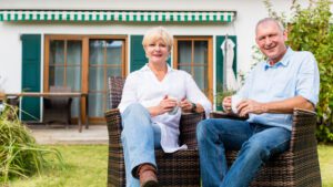 older man and woman sitting in garden in front of granny flat