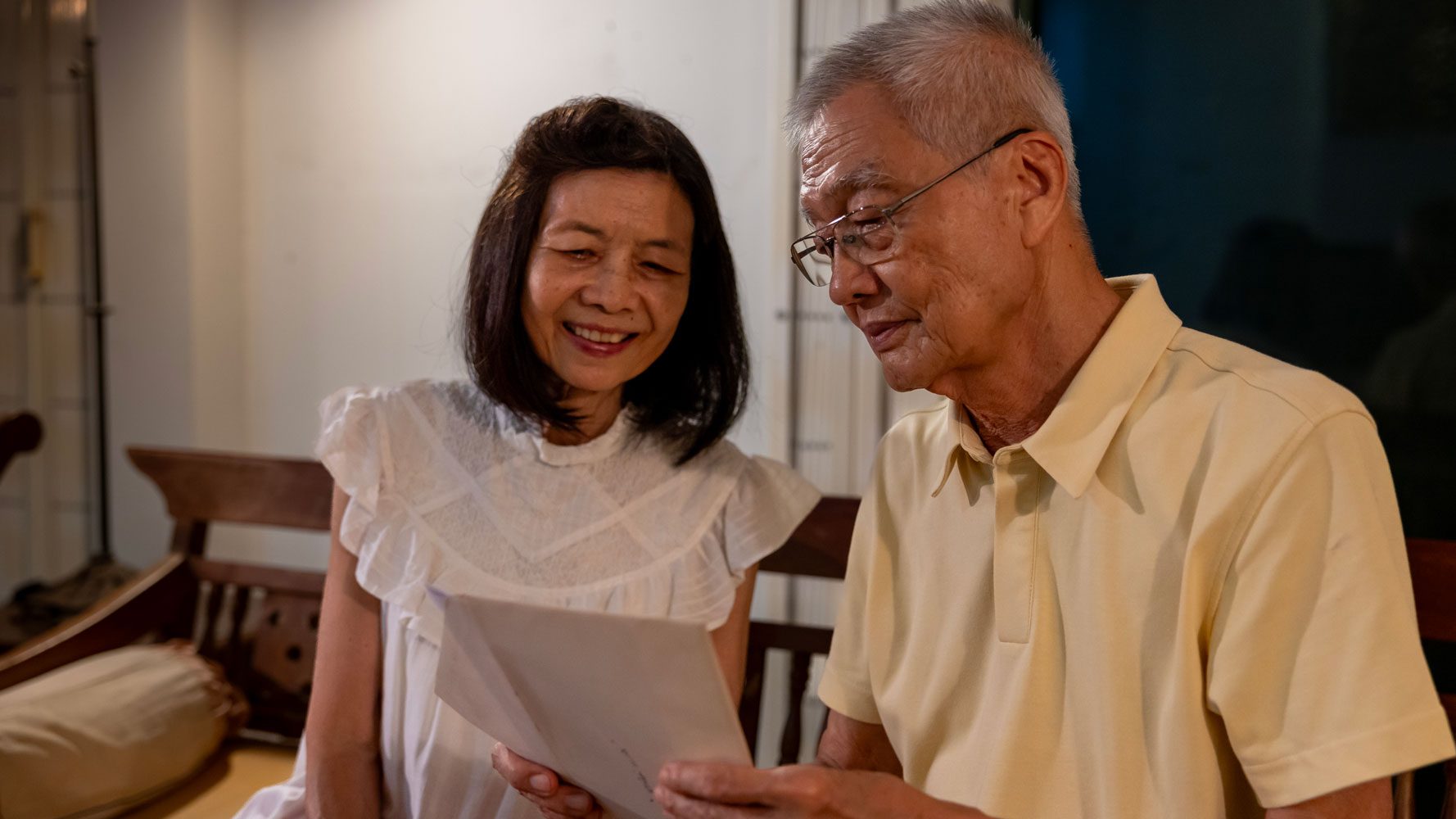 Older Asian couple reading support at home documentation
