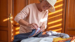 Older woman packing suitcase to go on holiday after pausing home care