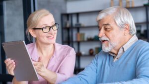An older man and woman sitting at a table with a tablet