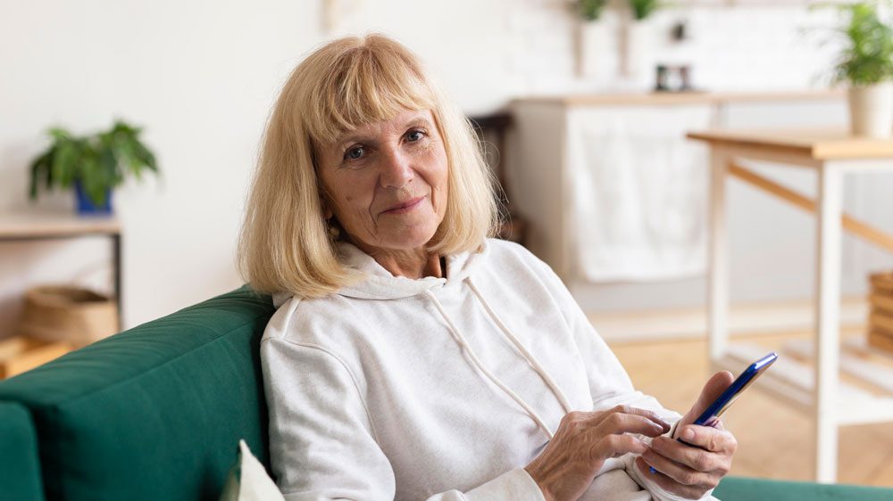 older woman at home with smartphone