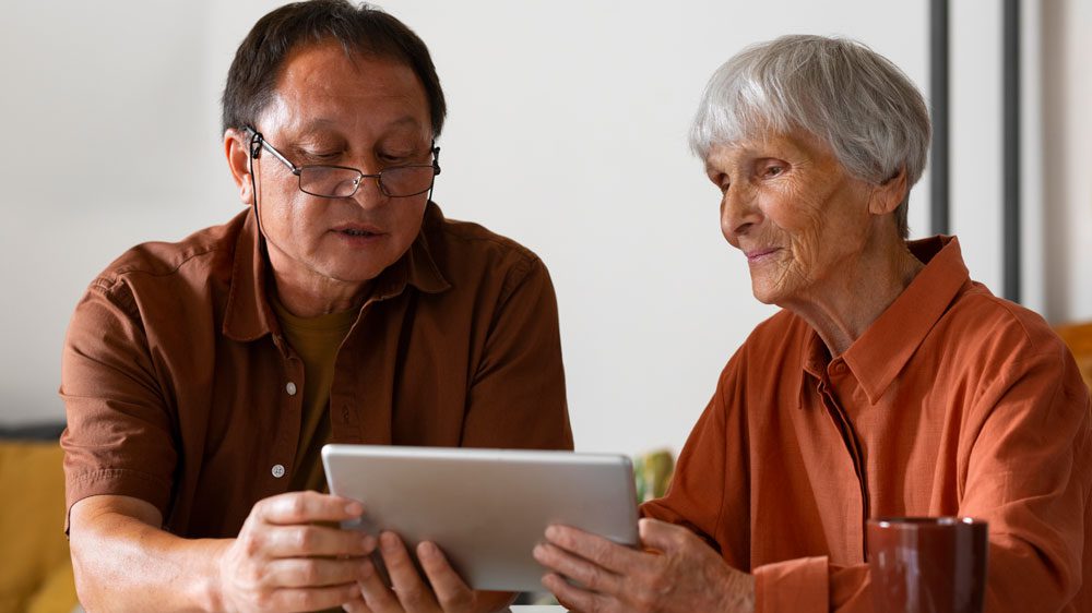 Older woman and her adult son reviewing aged care support information at a dining table