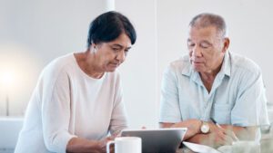 Older man and woman at a table with laptop working out Aged Care Fees