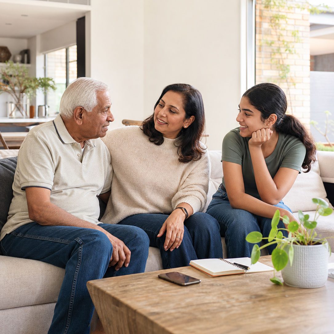 older father, adult daughter and teenage granddaughter talking together on a sofa at home