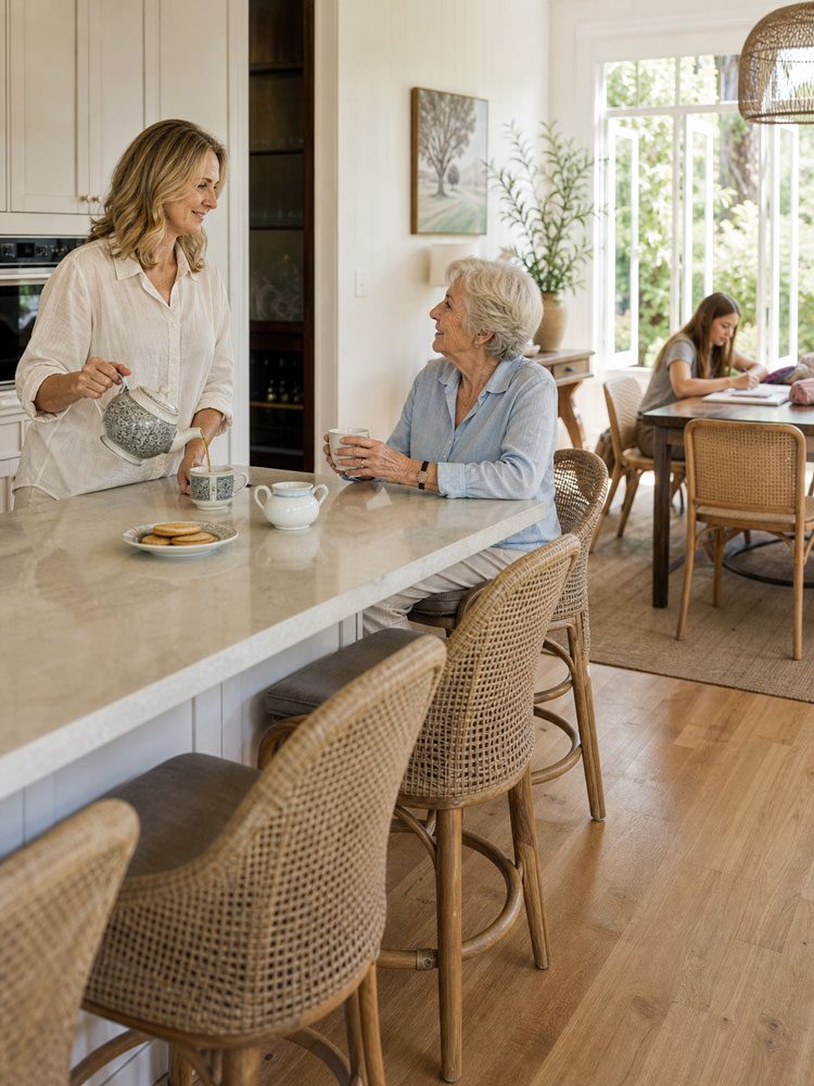 adult daughter and mother having tea with teenager in background